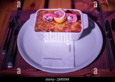 Pesce lasagne in una padella lucida sul tavolo Foto Stock