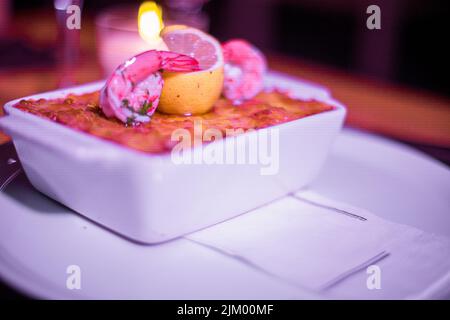 Pesce lasagne in una padella lucida sul tavolo Foto Stock