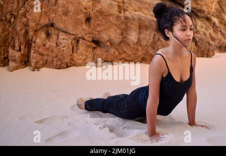 Trova un luogo che ti porta la pace e visitalo spesso. Una giovane donna che pratica lo yoga all'aperto. Foto Stock