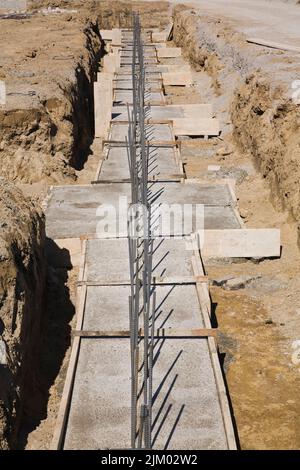 Scavo in cantiere con fondamenta in cemento armato per sostenere la parete di fondazione di un edificio. Foto Stock