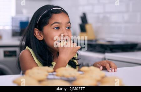 La mamma è davvero il miglior panettiere: Una bambina che si aiuta a fare biscotti appena sfornati a casa. Foto Stock