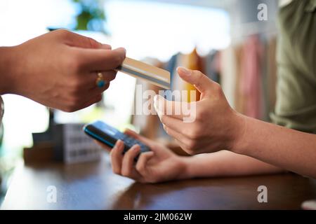 Fare scelte finanziarie intelligenti. Un cliente che dà la sua carta per effettuare un pagamento in un negozio. Foto Stock