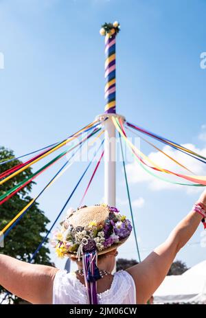 Un colpo verticale di femmina in un tradizionale cappello inglese ballando con un maypole al Countryfile Live Foto Stock