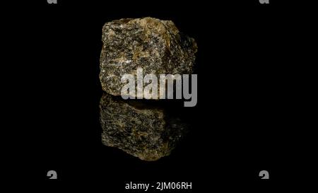 Primo piano di un quarzo dorato con piriti minerali isolati su una superficie nera riflettente Foto Stock