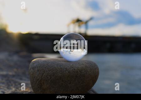 Una sfera di vetro riflettente su una roccia vicino ad una centrale elettrica Foto Stock