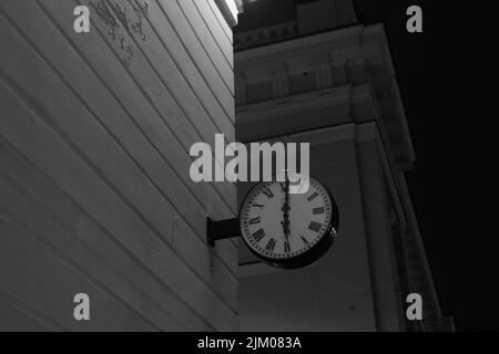 Un'immagine in scala di grigi con angolo basso di un orologio sul lato di un edificio Foto Stock