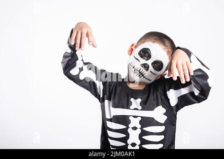 Halloween Kid. Bambino uomo horror viso pittura compongono per paura fantasma, ritratto di ragazzo asiatico bambino piccolo vestendo scheletro costume studio girato isolato Foto Stock