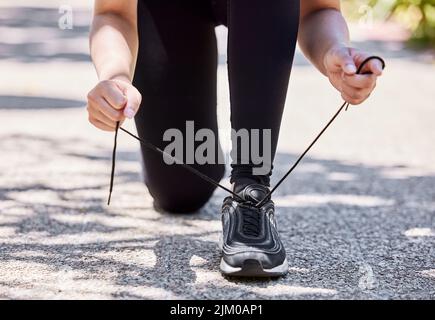 Lacci in su, lascia bruciare alcune calorie. Una donna che lega i suoi shoelaces prima di andare per una corsa all'aperto. Foto Stock