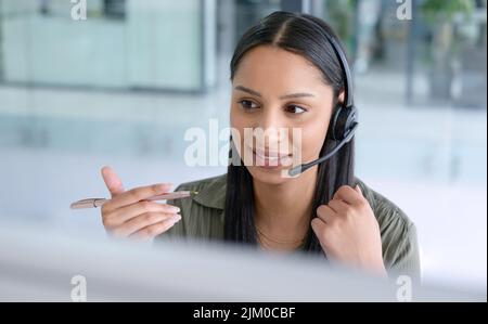 Generare interesse per i prodotti e i servizi della società. Un giovane agente del call center che lavora in un ufficio. Foto Stock