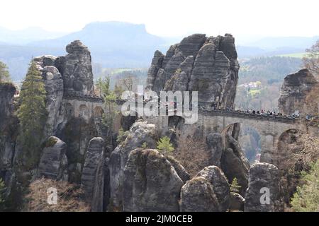 Una vista panoramica della formazione rocciosa di Bashtai e un ponte coperto di alberi in una giornata di sole in Germania Foto Stock