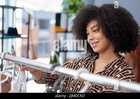 Sembra che abbia trovato un affare. Una giovane donna che acquista vestiti in un negozio. Foto Stock