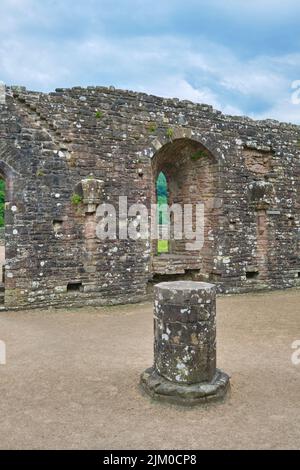 Un edificio senza tetto con le rovine di una fila di colonne di pietra che scendono dal centro della stanza. A Tintern Abby vicino a Chepstow, Galles, United Kin Foto Stock