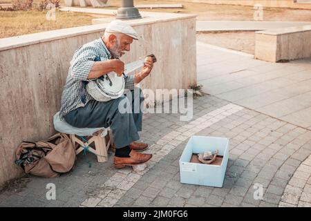 21 giugno 2022, Antalya, Turchia: Senior man che suona su strumenti musicali tradizionali folkloristici - saz e elemosina per strada della città Foto Stock