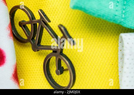 Un primo piano di un piccolo spilla per bicicletta su una t-shirt gialla, verde e bianca per il tour della Francia Foto Stock