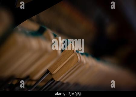 Un colpo di fuoco selettivo di martello da tastiera di legno sulle corde. Dentro la meccanica del pianoforte Foto Stock