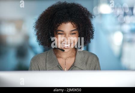 USA il sorriso per cambiare il mondo. Una giovane agente sorridente sul monitor con la cuffia accesa mentre lavora in un call center. Foto Stock