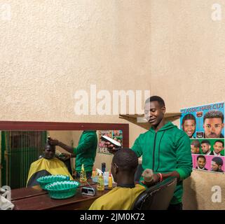 Un uomo nero seduto mentre i capelli si rifilano in un barbiere in Ruanda Foto Stock