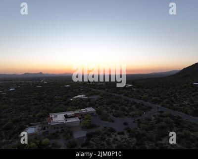 Una strada vuota circondata da piante verdi sullo sfondo di un bellissimo tramonto Foto Stock