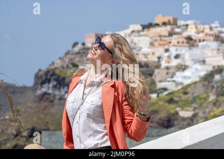 Una foto poco profonda di una bella donna caucasica che si posa su uno sfondo dell'architettura unica di Santorini, Grecia Foto Stock