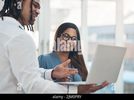 Semplificare le attività per andare avanti. Due uomini d'affari che utilizzano un notebook insieme in ufficio. Foto Stock
