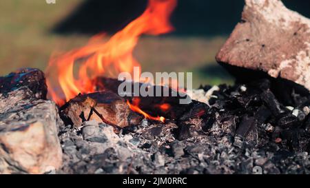 Un primo piano di un falò con legna che brucia in esso e fiamme che escono su uno sfondo sfocato Foto Stock