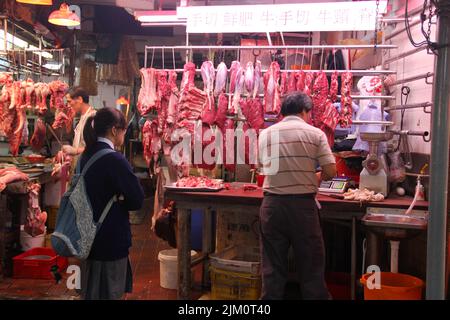 Una studentessa attende un ordine presso uno stallo di macelleria a Hong Kong, in Cina Foto Stock