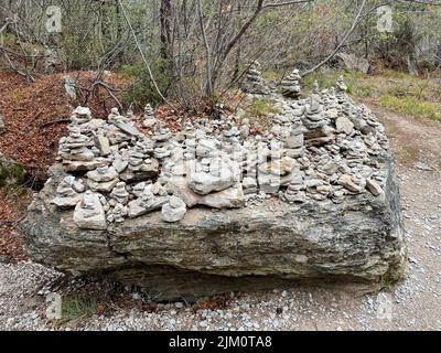 Pietre di dimensioni diverse sulla cima di una grande pietra in una foresta Foto Stock