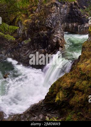 Una cascata che si innalza lungo una scogliera coperta di muschio secco. Foto Stock