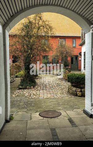 Tipico cortile con giardino visto da un passaggio coperto nella città di Assens. Assen, Fyn, Danimarca, Europa Foto Stock