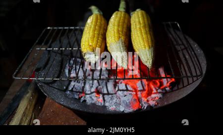 Il mais delizioso viene venduto per strada. Maize arrostite e cotte in vendita. Cornici grigliate sulla griglia, pronte da servire. Immagine a fuoco selettivo Foto Stock