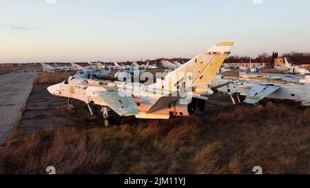 Volo di vista con droni aerei sopra il parcheggio molti vecchi aerei smantellati. Cimitero di aerei rotti in crash all'alba del tramonto. Primo piano vista dall'alto aeroplano abbandonato, vecchio combattente aereo militare Foto Stock