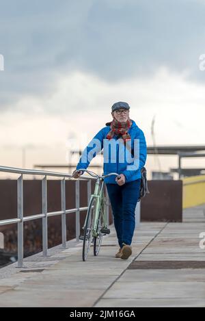Ritratto senior uomo a camminare con la sua bicicletta accanto al mare Foto Stock