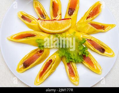 Pancake ripieni di pesce rosso e tagliati a pezzi. Piatto con pancake da vicino. Foto Stock