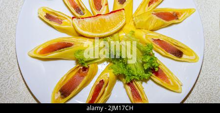 Pancake ripieni di pesce rosso e tagliati a pezzi. Piatto con pancake da vicino. Foto Stock