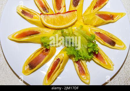 Pancake ripieni di pesce rosso e tagliati a pezzi. Piatto con pancake da vicino. Foto Stock