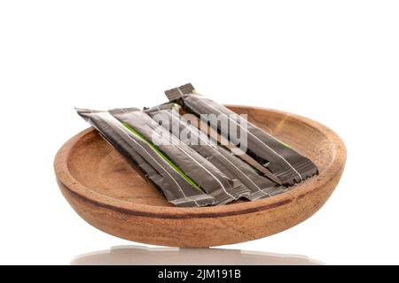 Quattro bastoncini di zucchero in sacchetti di carta su un piatto di legno, primo piano, isolato su sfondo bianco. Foto Stock