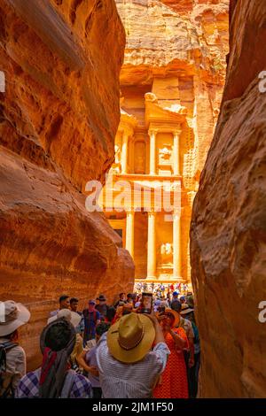 La folla guarda il primo sguardo del palazzo del Tesoro da al Siq in Petra Jordan. Foto Stock