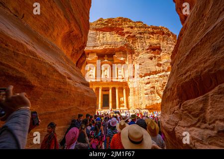 La folla guarda il primo sguardo del palazzo del Tesoro da al Siq in Petra Jordan. Foto Stock