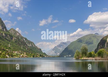 Foto panoramica delle acque calme del lago d'Idro (Lago d'Idro) circondato da rocce e montagne boscose. Brescia, Lombardia, Italia Foto Stock