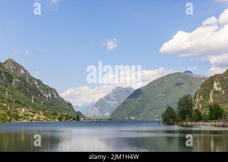 Leggera foschia estiva dall'evaporazione sulle acque di un lago alpino Idro (Lago d'Idro) circondato da alte montagne rocciose boscose. Brescia, Lombardia Foto Stock