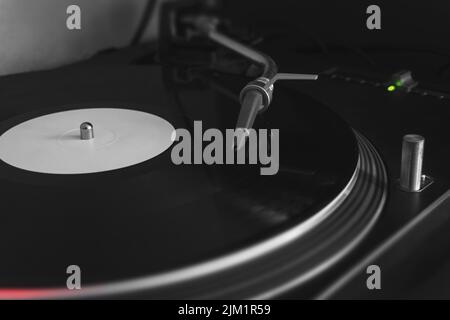 Giradischi lettore che riproduce vinile bianco con ago stilo, primo piano, messa a fuoco selettiva. Bianco e nero con colori selettivi. Foto Stock