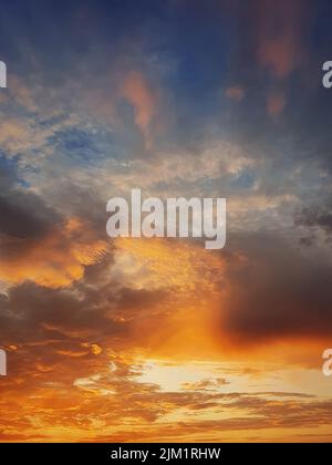 Bellissimo cielo al tramonto con colorate nuvole arancioni sull'orizzonte, sfondo celeste verticale Foto Stock