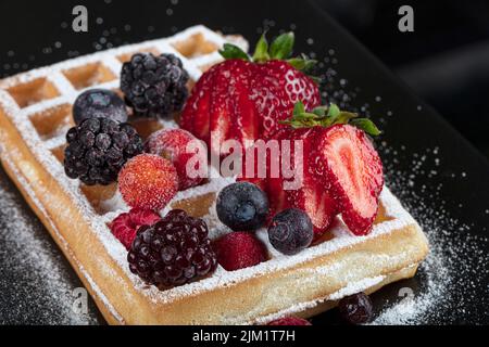 Cialde belghe tradizionali con gelato e salsa di frutta alle bacche sul piatto, focus selettivo e spazio libero. Macrosato di cialde con, mirtilli , b Foto Stock