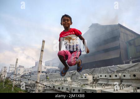 Dhaka, Bangladesh. 03rd ago 2022. Un bambino si vede giocare in un'atmosfera inquinata dall'aria a Dhaka. La maggior parte dei laminatoi di acciaio all'interno e intorno alla capitale sono stati in funzione senza il necessario sistema di controllo dell'inquinamento atmosferico che presenta un rischio di inquinamento atmosferico e di pericolo per la salute, secondo quanto risulta dal Dipartimento dell'ambiente (Doe). Credit: SOPA Images Limited/Alamy Live News Foto Stock