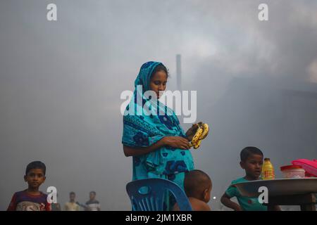 Dhaka, Bangladesh. 03rd ago 2022. Una donna incinta acquista banane in un'atmosfera inquinata dall'aria a Dhaka. La maggior parte dei laminatoi di acciaio all'interno e intorno alla capitale sono stati in funzione senza il necessario sistema di controllo dell'inquinamento atmosferico che presenta un rischio di inquinamento atmosferico e di pericolo per la salute, secondo quanto risulta dal Dipartimento dell'ambiente (Doe). Credit: SOPA Images Limited/Alamy Live News Foto Stock