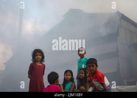 Dhaka, Bangladesh. 03rd ago 2022. I bambini giocano in un'atmosfera inquinata dall'aria a Dhaka. La maggior parte dei laminatoi di acciaio all'interno e intorno alla capitale sono stati in funzione senza il necessario sistema di controllo dell'inquinamento atmosferico che presenta un rischio di inquinamento atmosferico e di pericolo per la salute, secondo quanto risulta dal Dipartimento dell'ambiente (Doe). Credit: SOPA Images Limited/Alamy Live News Foto Stock