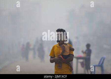 Dhaka, Bangladesh. 03rd ago 2022. Un uomo è visto con la figlia in un'atmosfera inquinata dall'aria a Dhaka. La maggior parte dei laminatoi di acciaio all'interno e intorno alla capitale sono stati in funzione senza il necessario sistema di controllo dell'inquinamento atmosferico che presenta un rischio di inquinamento atmosferico e di pericolo per la salute, secondo quanto risulta dal Dipartimento dell'ambiente (Doe). Credit: SOPA Images Limited/Alamy Live News Foto Stock