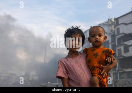 Dhaka, Bangladesh. 03rd ago, 2022. I bambini posano per una foto in un'atmosfera inquinata dall'aria a Dhaka. La maggior parte dei laminatoi di acciaio all'interno e intorno alla capitale sono stati in funzione senza il necessario sistema di controllo dell'inquinamento atmosferico che presenta un rischio di inquinamento atmosferico e di pericolo per la salute, secondo quanto risulta dal Dipartimento dell'ambiente (Doe). Credit: SOPA Images Limited/Alamy Live News Foto Stock