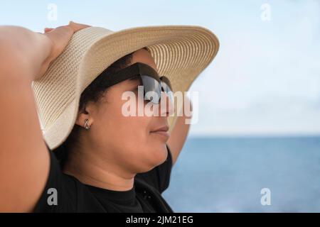 Primo piano di una donna con occhiali rilassanti vicino al mare Foto Stock