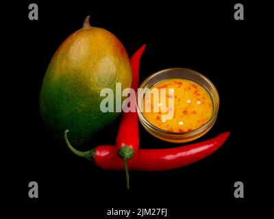 Confettura di peperoncini, peperoncini e mango verde-giallo su sfondo nero puro. Foto Stock
